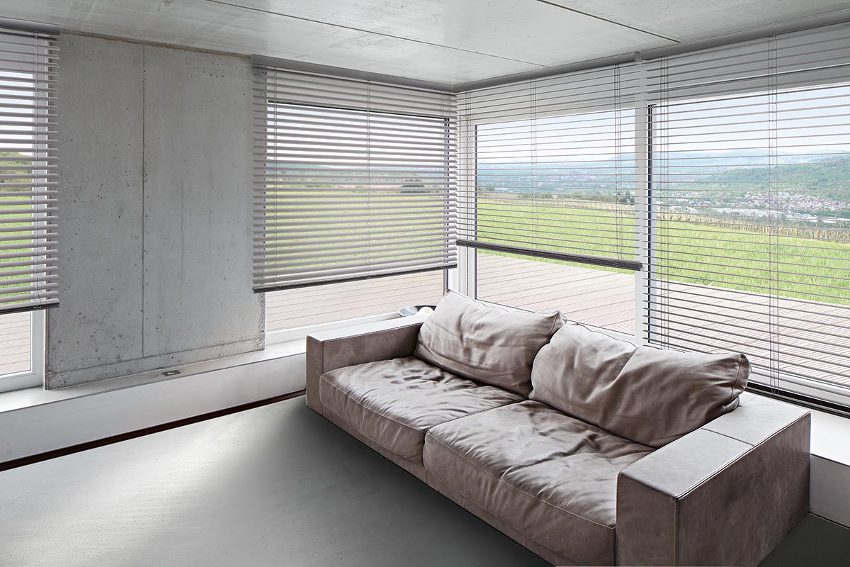 Eine Horizontal-Jalousie als Sonnenschutz in einem modernen Wohnzimmer